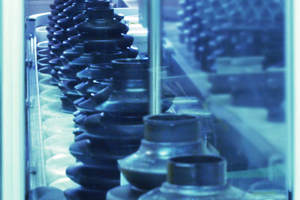 Close-up of various black, stacked industrial gears reflected in a glass surface. The blue tone gives a cool, mechanical, and orderly feel.